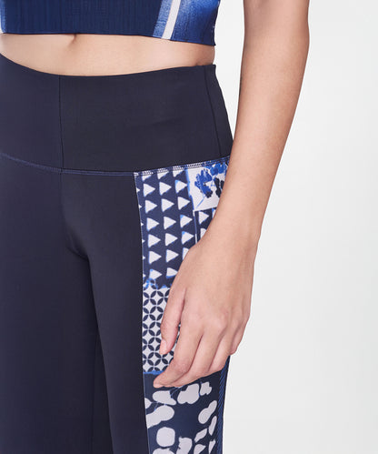 A person wearing the Indigo Printed Top With Leggings, featuring navy blue leggings with white and blue geometric side panels, ideal for an athleisure style.