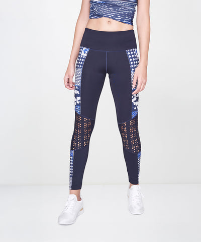 Woman wears the Indigo Printed Top With Leggings, featuring a patterned navy blue design, styled with white sneakers and an athleisure vibe against a plain light background.