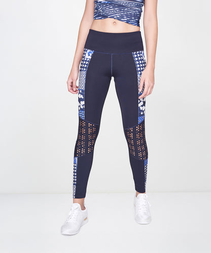 Woman wears the Indigo Printed Top With Leggings, featuring a patterned navy blue design, styled with white sneakers and an athleisure vibe against a plain light background.