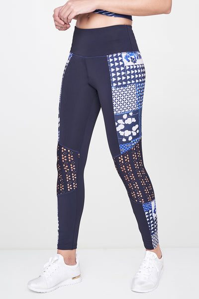 Woman wears the Indigo Printed Top With Leggings in navy and blue patterns, paired with white sneakers, cropped at the shoulders for a sleek athleisure style.