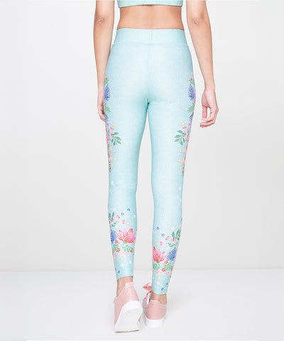 A woman is seen from the back against a plain background, wearing Aqua Printed Leggings and pink shoes.