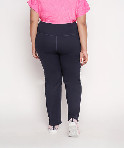 A person wearing a pink top, pink shoes, and Tuna London Iris Navy Polyblend Track Pant for women stands facing away from the camera.