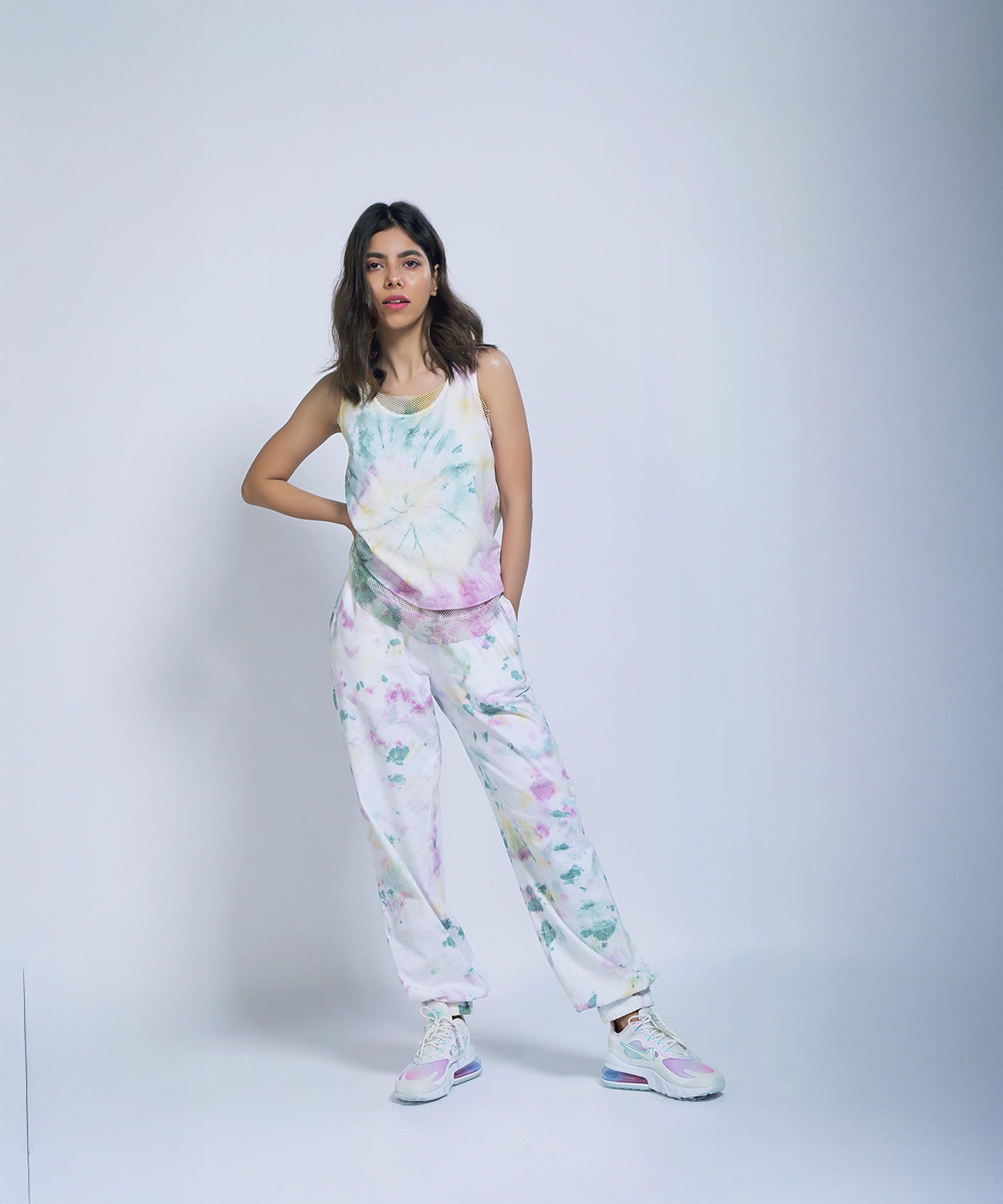Woman modeling Comfort Fit Joggers and a Netted Tank Top, paired with pastel sneakers, against a plain light background.