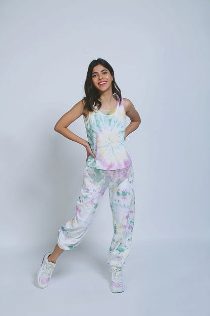Woman smiling in Comfort Fit Joggers and Netted Tank Top, posing playfully in sneakers against a plain background, showcasing relaxed, versatile style with this multi-purpose set.