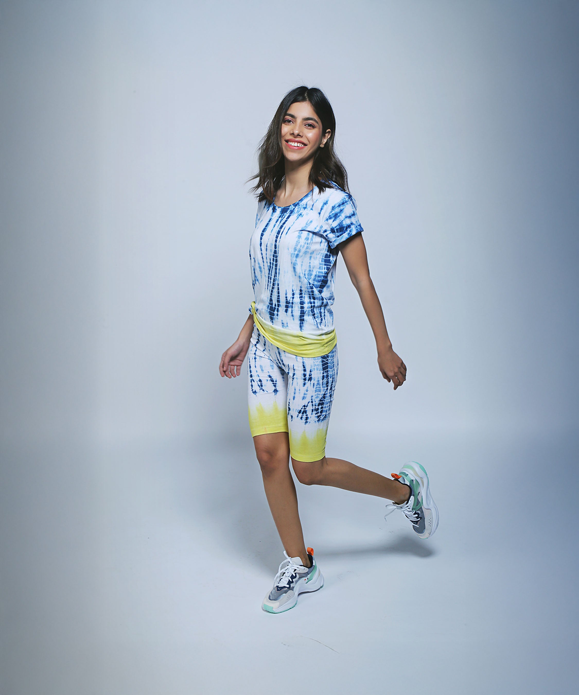 Wearing the Comfort Fit Tee and Biker Shorts set, she smiles in the studio—her 100% cotton outfit offers vibrant style and all-day comfort.