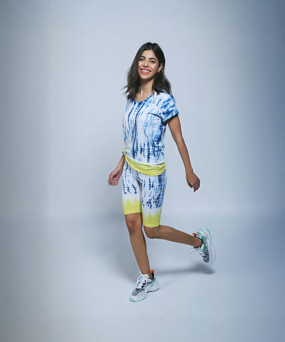 Wearing the Comfort Fit Tee and Biker Shorts set, she smiles in the studio—her 100% cotton outfit offers vibrant style and all-day comfort.
