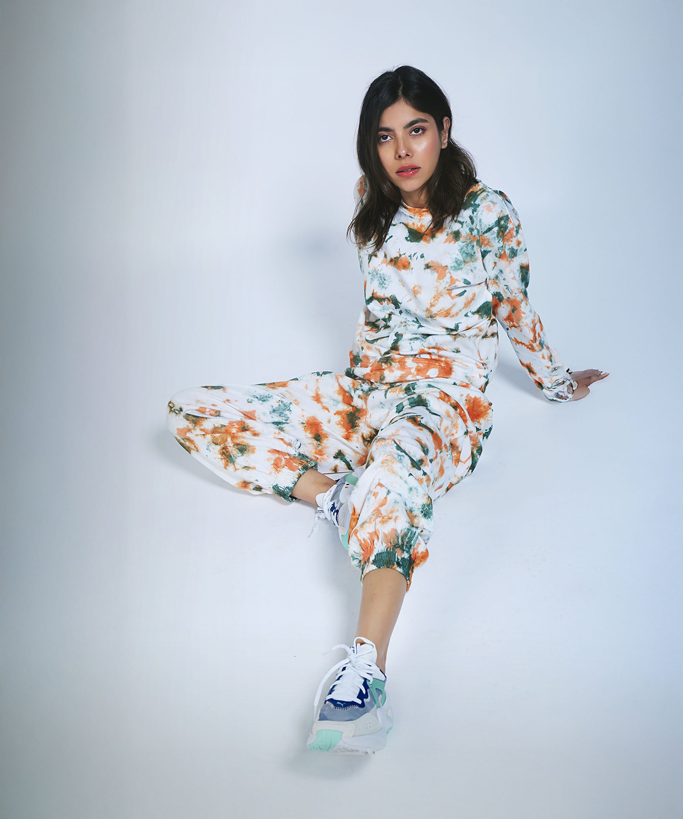 Woman in an Earthy Tones Sweatshirt / Tee and Comfort Joggers, sitting on the floor with one leg extended, looking at the camera.