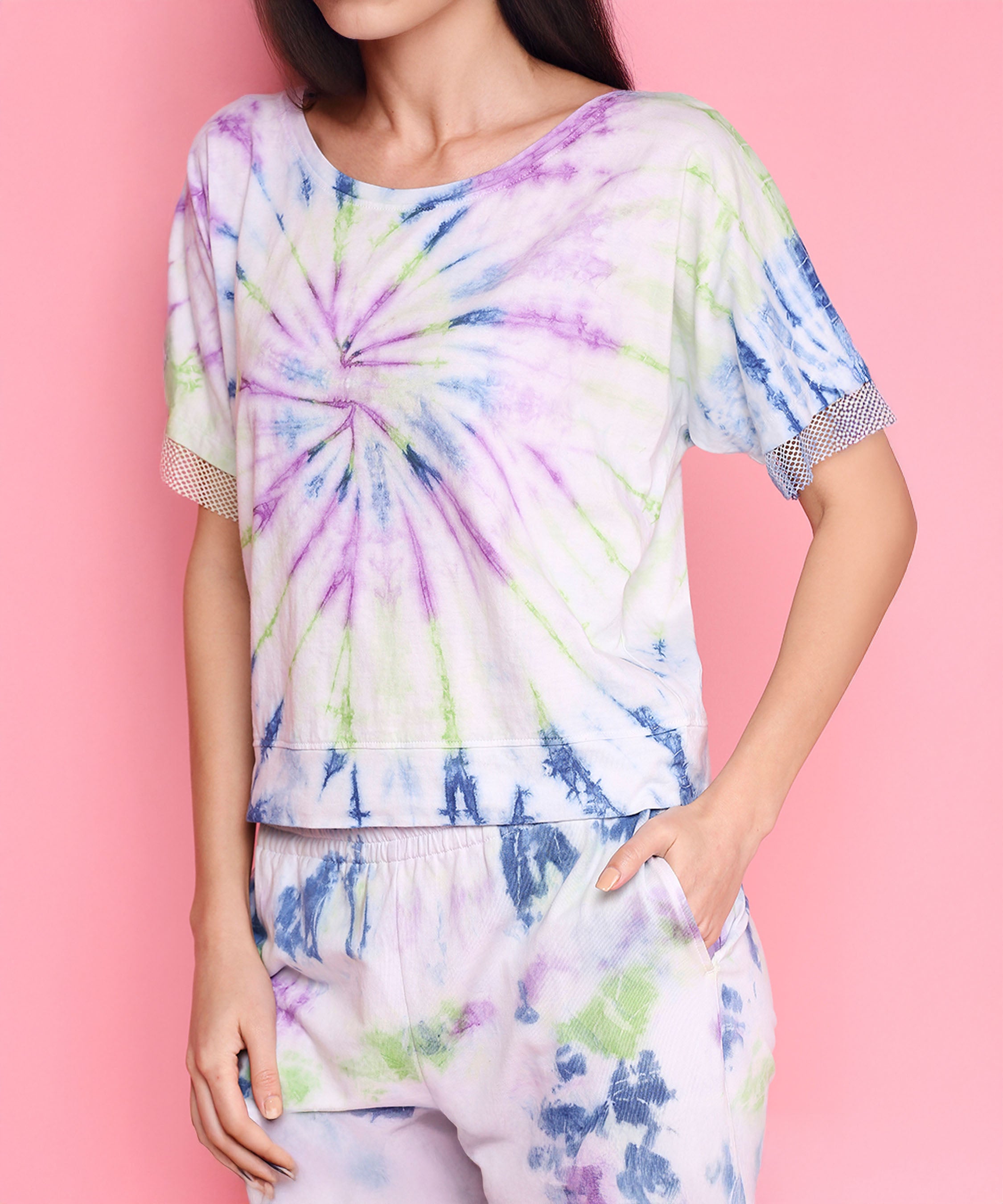 Woman wearing the Comfort Fit Tee + Joggers - AW21 set in pastel colors, standing against a pink background.