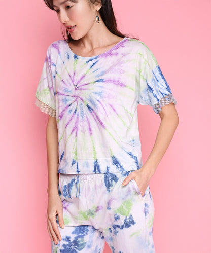 Woman wears the Comfort Fit Tee + Joggers - AW21, made from breathable, hand-dyed fabric. She stands against a pink background, looking down with her hand in the pocket.