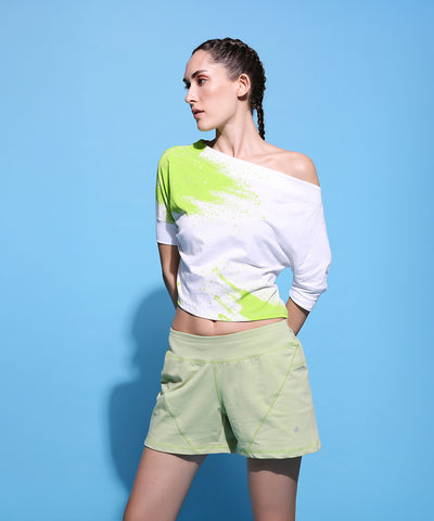 Woman wears the AW21 One Side Off Shoulder Crop Top with matching shorts, posing against a light blue background.