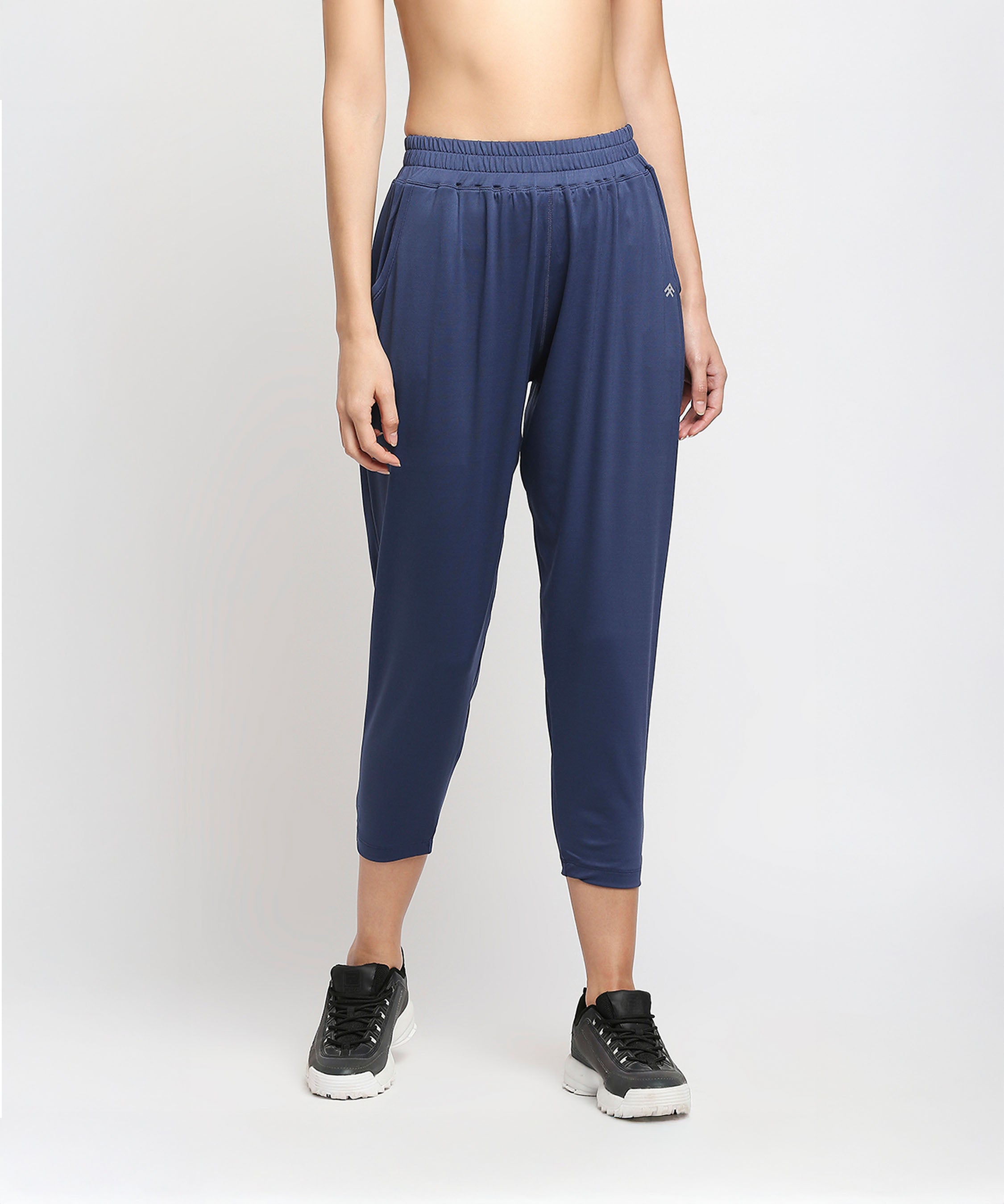 A person wearing Blue Yoga Pants - AW21 with a relaxed fit and black sneakers stands against a plain light background.