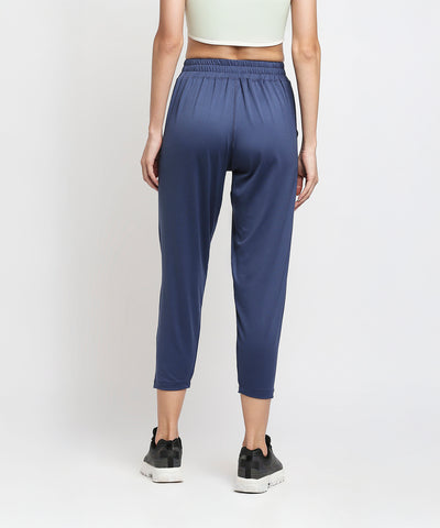 A person shown from the back wearing relaxed fit Blue Yoga Pants - AW21, black sneakers, and a light green crop top.