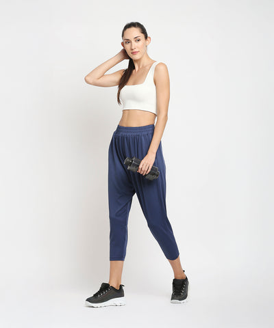 Woman in workout clothes holding a dumbbell, standing against a plain white background, wearing Blue Yoga Pants - AW21 for ultimate comfort during any workout.