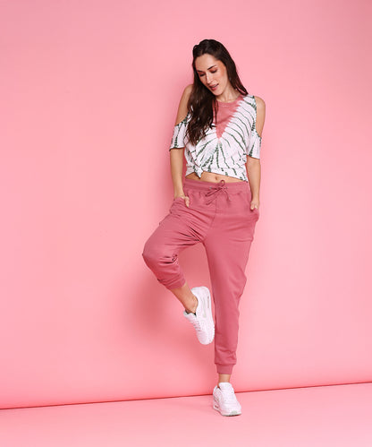 A woman poses in the Cold Shoulder Comfort Fit Top + Joggers - AW21 set, showcasing casual style with playful elegance.