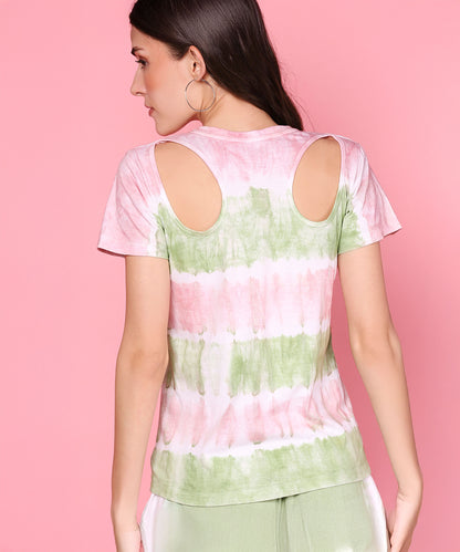 Woman in the Tee With Racer Back Cut + Joggers - AW21, a pastel pink tee with back cut-out and mint green joggers, stands against a pink background, highlighting this stylish hand-dyed set.