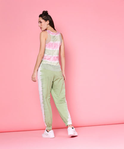 Model wears the Comfort Fit Joggers + Netted Tank Top - AW21 in mint green and pastel, standing against a pink background facing away.