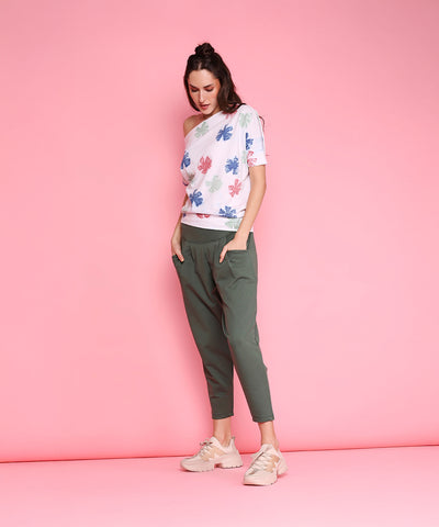 Woman in Pleated Yoga Pants - AW21 stands against a pink background, looking down with hands in pockets.