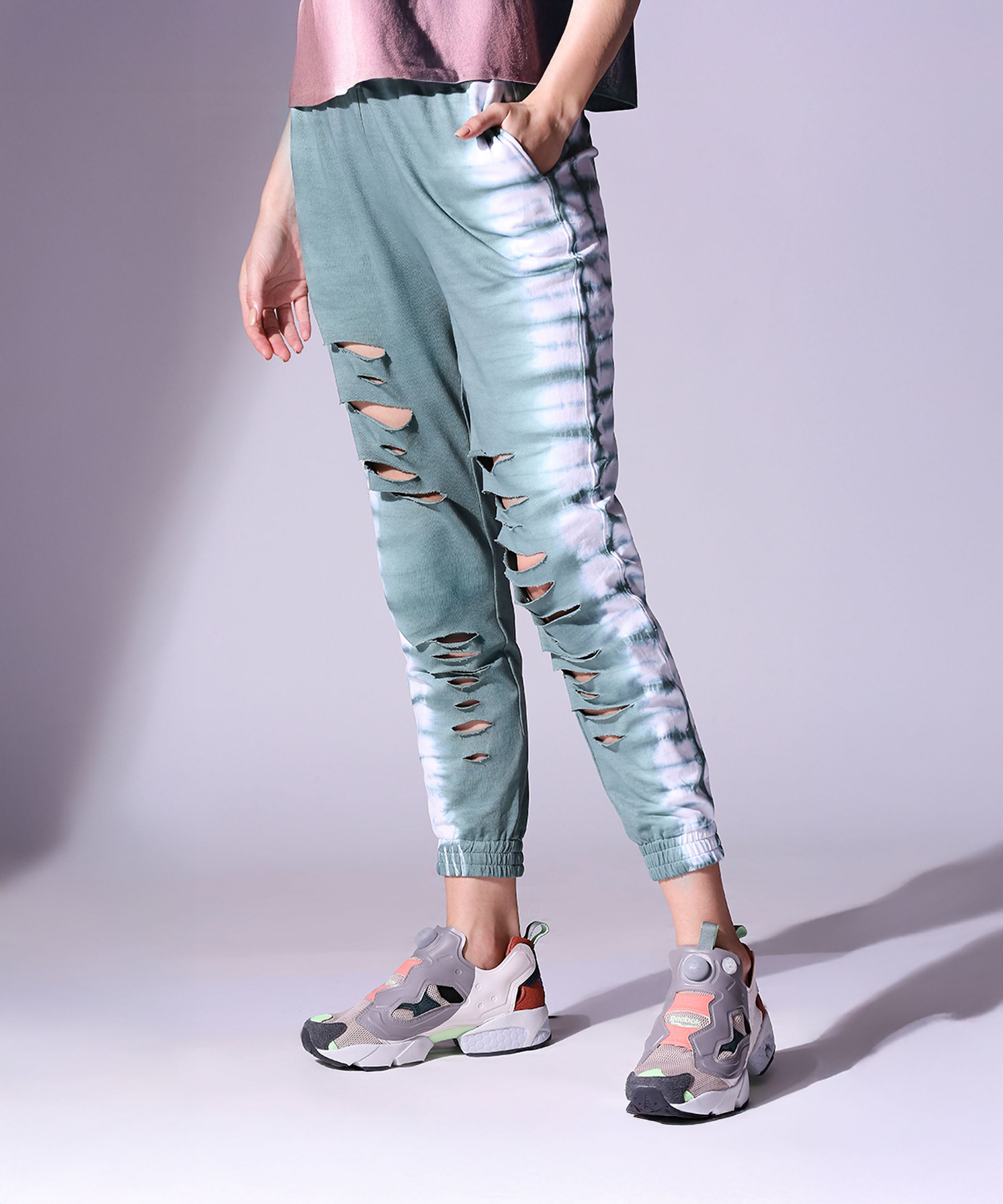 Model wears the Comfort Fit Tie Dye Top and Ripped Tie Dye Joggers - AW21 in teal with white tie-dye stripes, paired with grey sneakers against a light background—ideal for autumn-winter style.