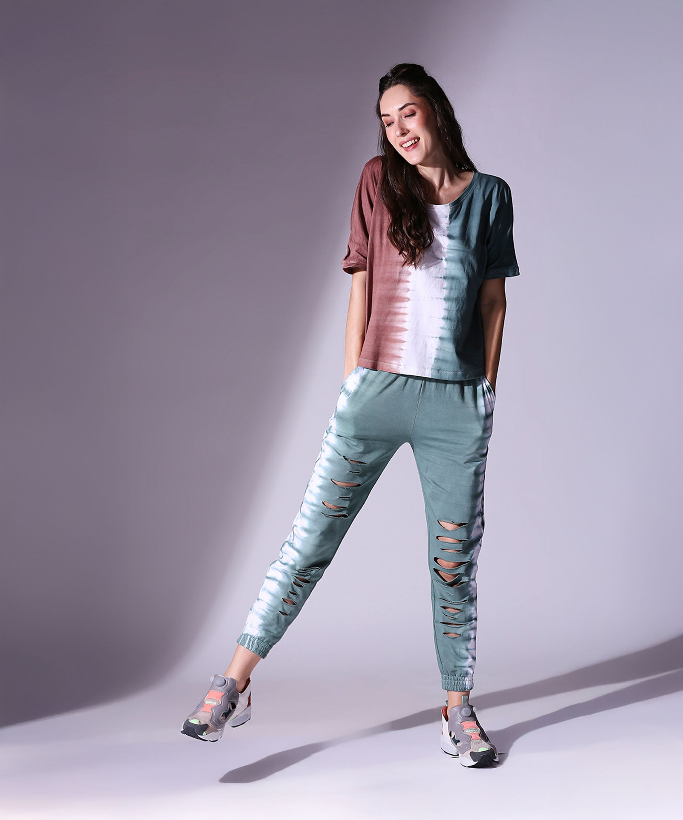 A smiling woman models the Comfort Fit Tie Dye Top and Ripped Tie Dye Joggers - AW21, standing with hands in pockets against a light background—ideal for autumn winter style.