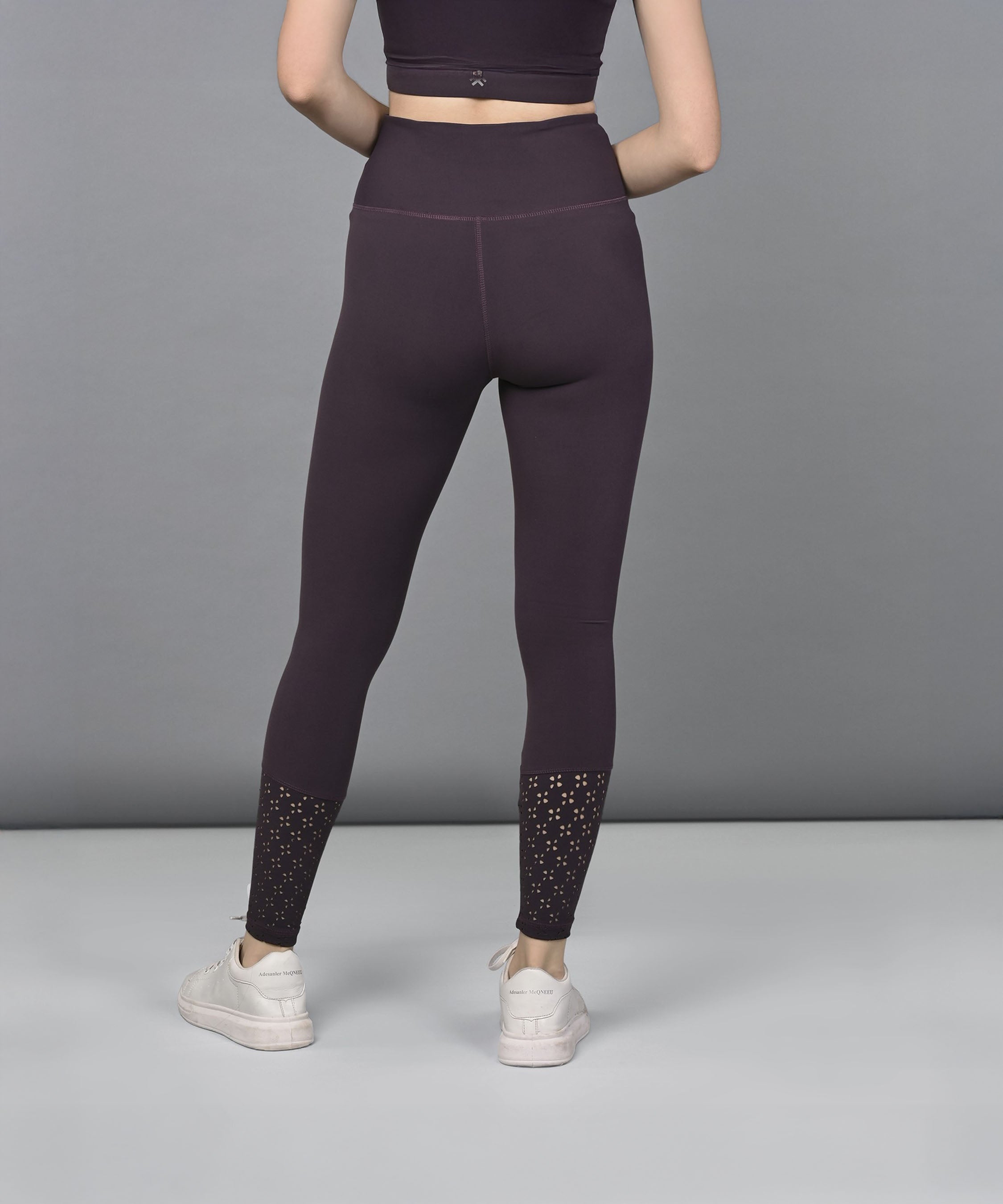 Woman wearing Wine Leggings with calf cutouts, paired with white sneakers and a matching crop top, facing away.
