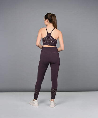 A woman wearing Wine Leggings stands facing away with her hands behind her back, set against a plain gray background.