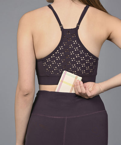 Wearing the Wine Netted Top, a woman in workout clothes slips a small wallet into the back waistband pocket of her leggings.