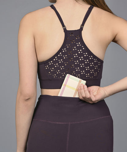 Wearing the Wine Netted Top, a woman in workout clothes slips a small wallet into the back waistband pocket of her leggings.