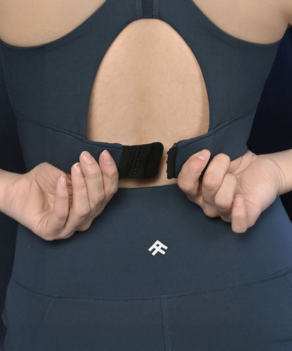 Person fastening a Teal Netted Top at the back, paired with navy blue activewear.