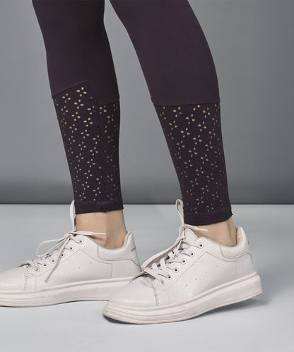 A person wearing white sneakers and black leggings with a cutout pattern near the ankles, paired with the Wine Netted Top.