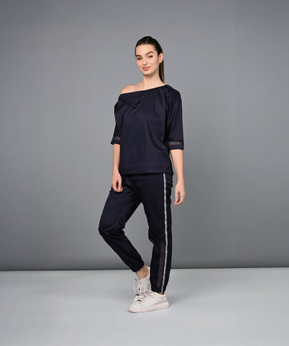 A woman wears the Off Shoulder Nebula Navy Co-ord Set, made from 100% cotton with matching side-striped pants, posed against a gray background.