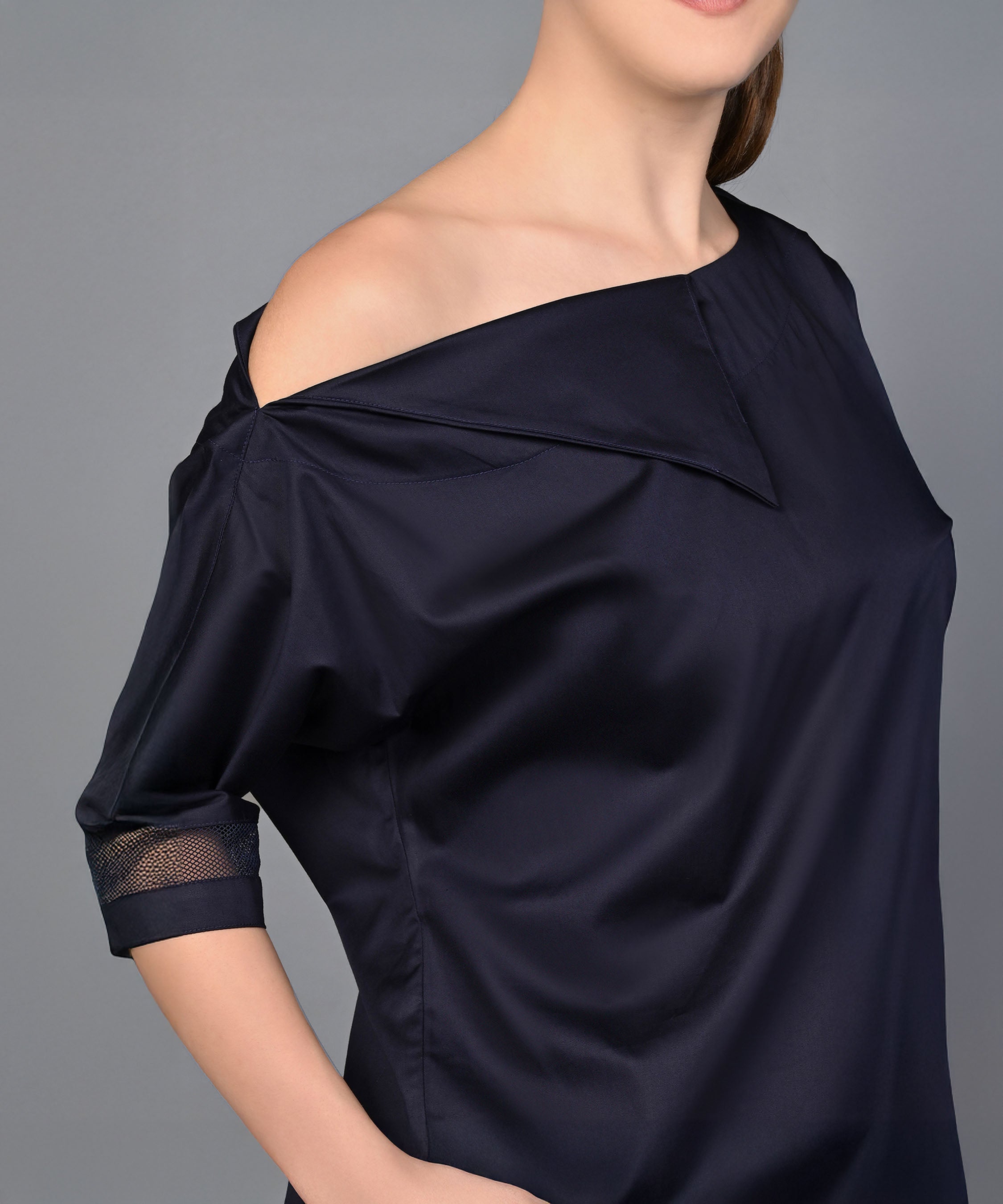 Woman wearing the Off Shoulder Nebula Navy Co-ord set, made from 100% cotton, with one hand in her pocket, standing against a plain grey background.