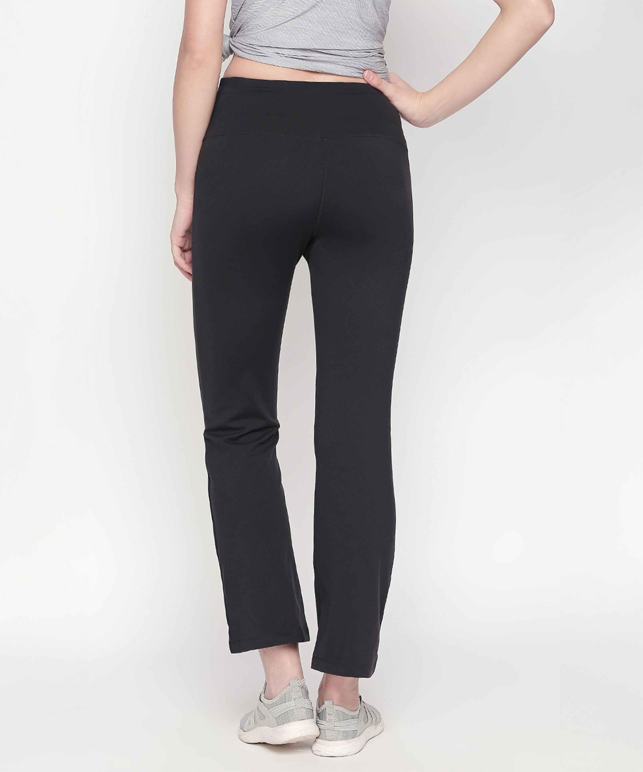 Person wearing Bootcut High Waisted Workout Pants in black with a high-rise waistband, gray top, and gray sneakers, standing with back facing the camera.