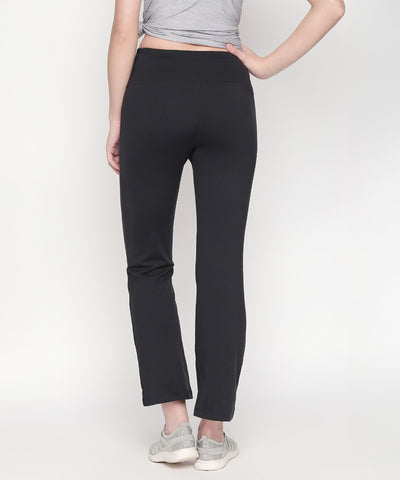 Person wearing Bootcut High Waisted Workout Pants in black with a high-rise waistband, gray top, and gray sneakers, standing with back facing the camera.
