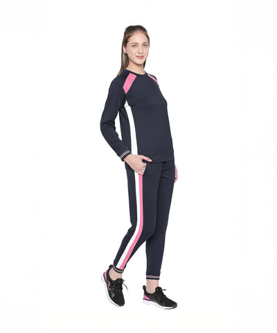 A woman stands and smiles in Navy Blue Joggers with pink and white side stripes, perfect for sports or casual outings, set against a white background.