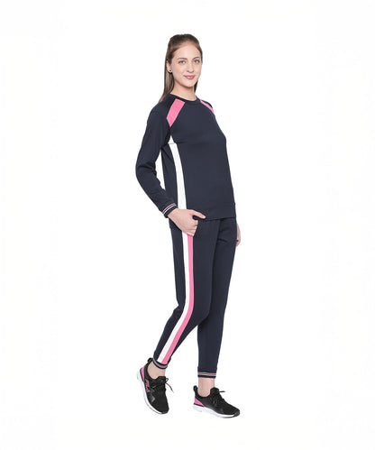 A woman stands and smiles in Navy Blue Joggers with pink and white side stripes, perfect for sports or casual outings, set against a white background.