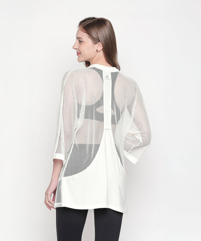 Woman in a Loose Fit 3/4th Sleeve White Shrug and black leggings stands with her back to the camera against a white background, highlighting a stylish athleisure ensemble.
