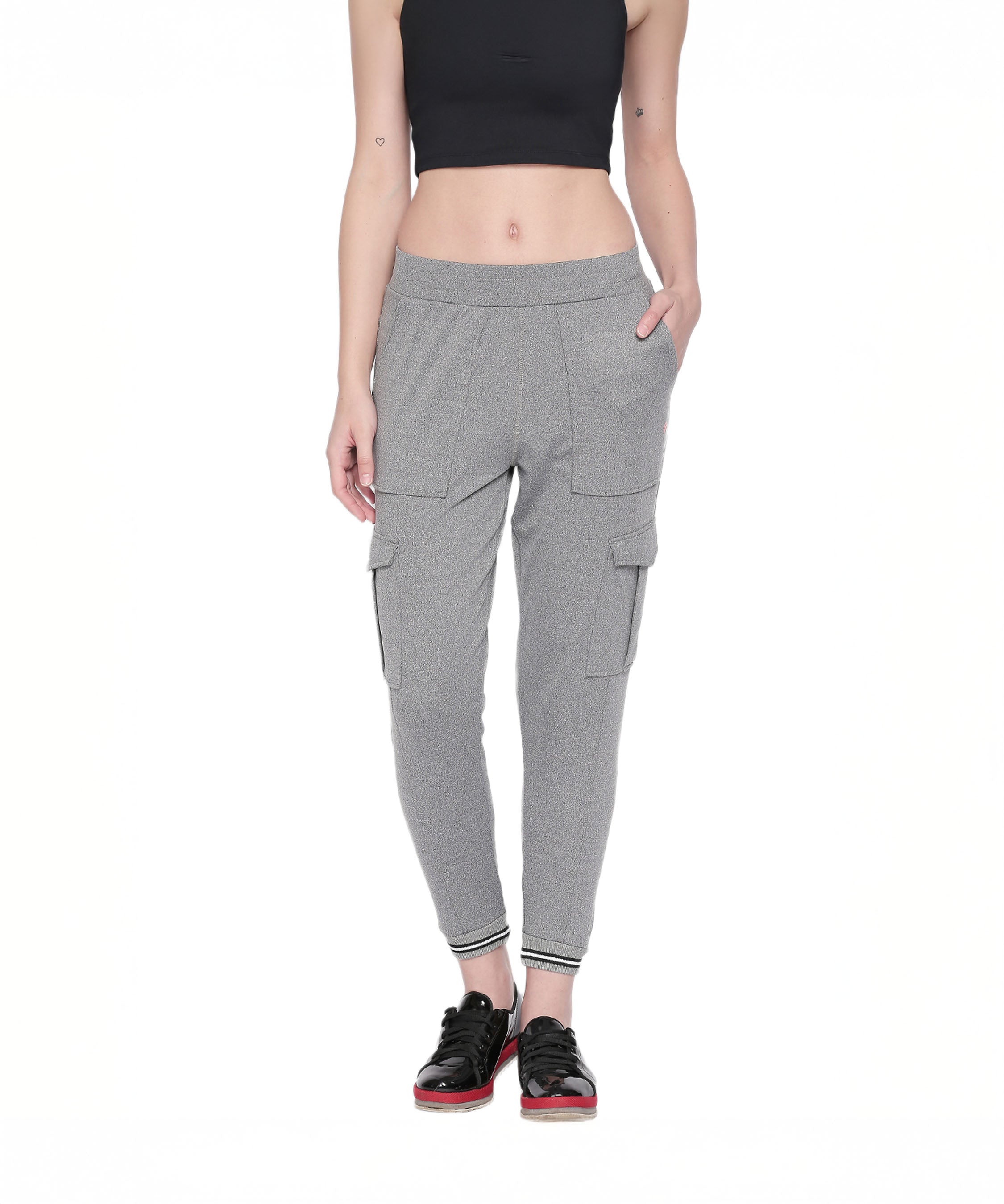 Woman in a black crop top and Grey Cargo Pants with a side pocket, standing with one hand in her pocket and wearing black sneakers.