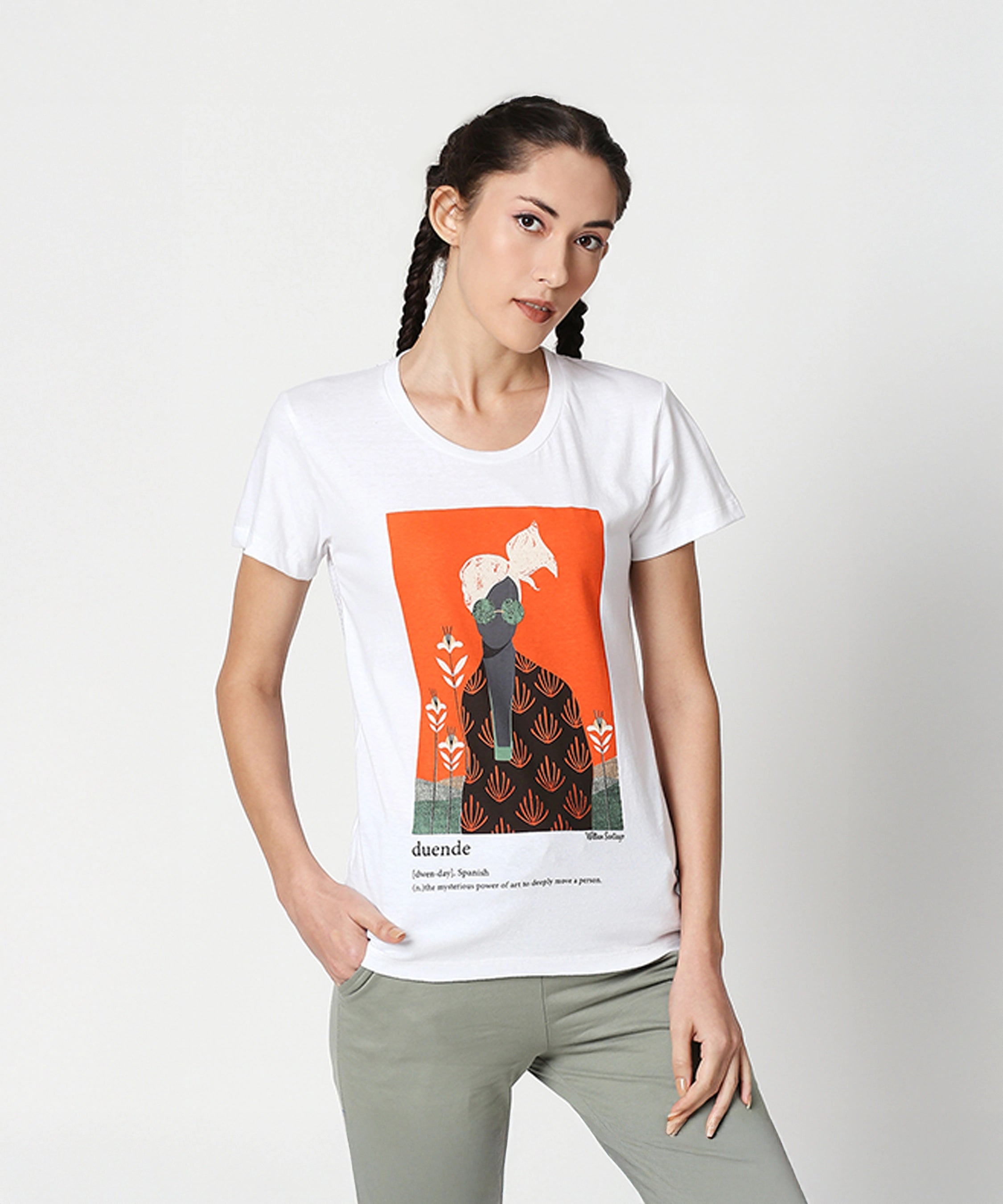 A woman with braided hair wears the Duende Printed cotton tee and light green pants, posing with one hand in her pocket.