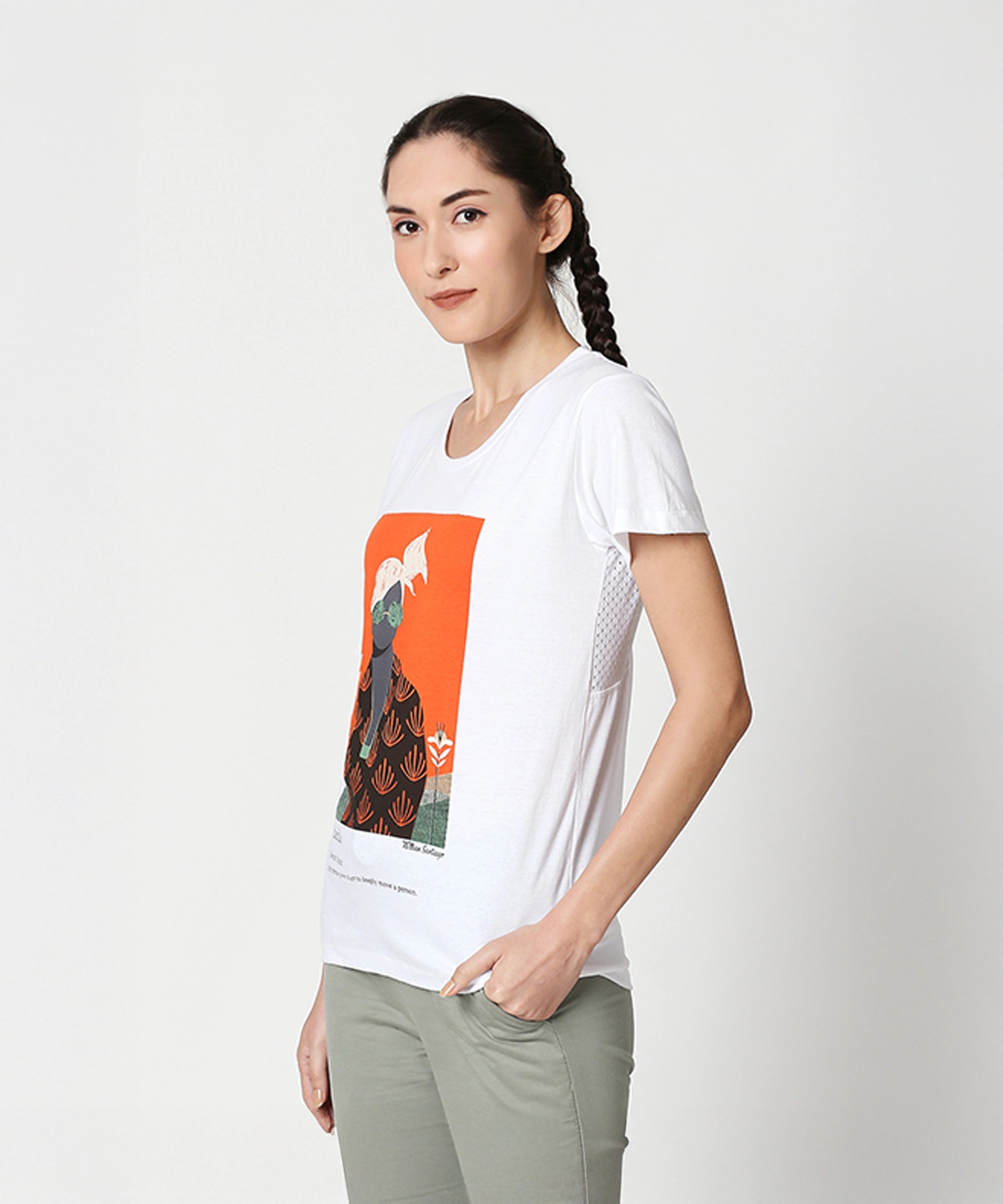 Woman with braided hair, smiling sideways, wears the Duende Printed cotton tee and light green pants.