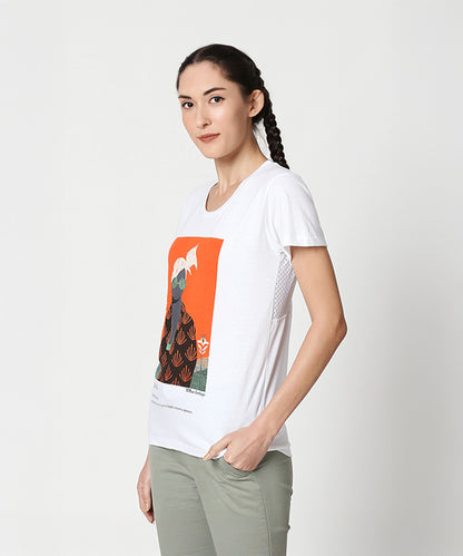 Woman with braided hair, smiling sideways, wears the Duende Printed cotton tee and light green pants.