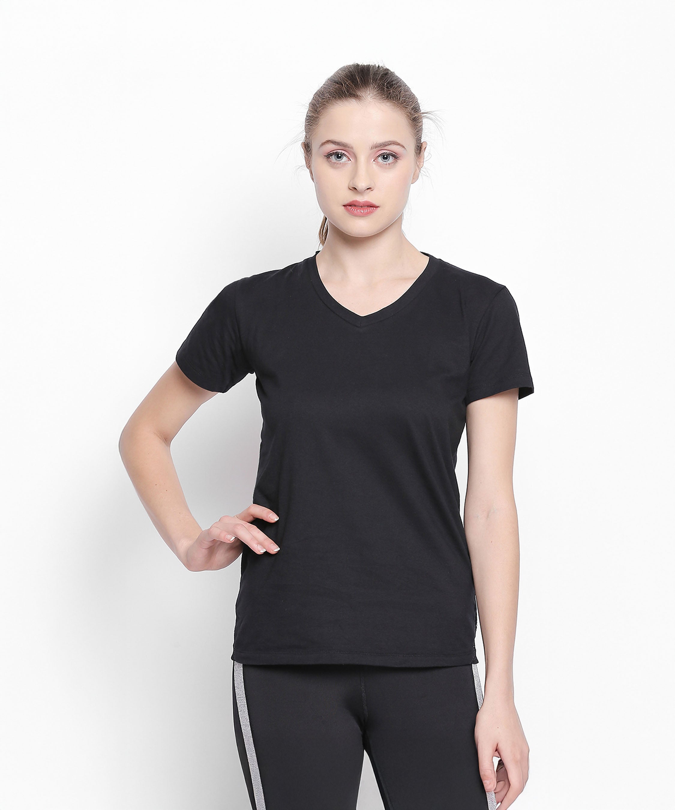 A woman wears the Tuna London Sara Basic Sports Tee With Net Detailing for Women and black pants with white stripes, standing against a plain white background.