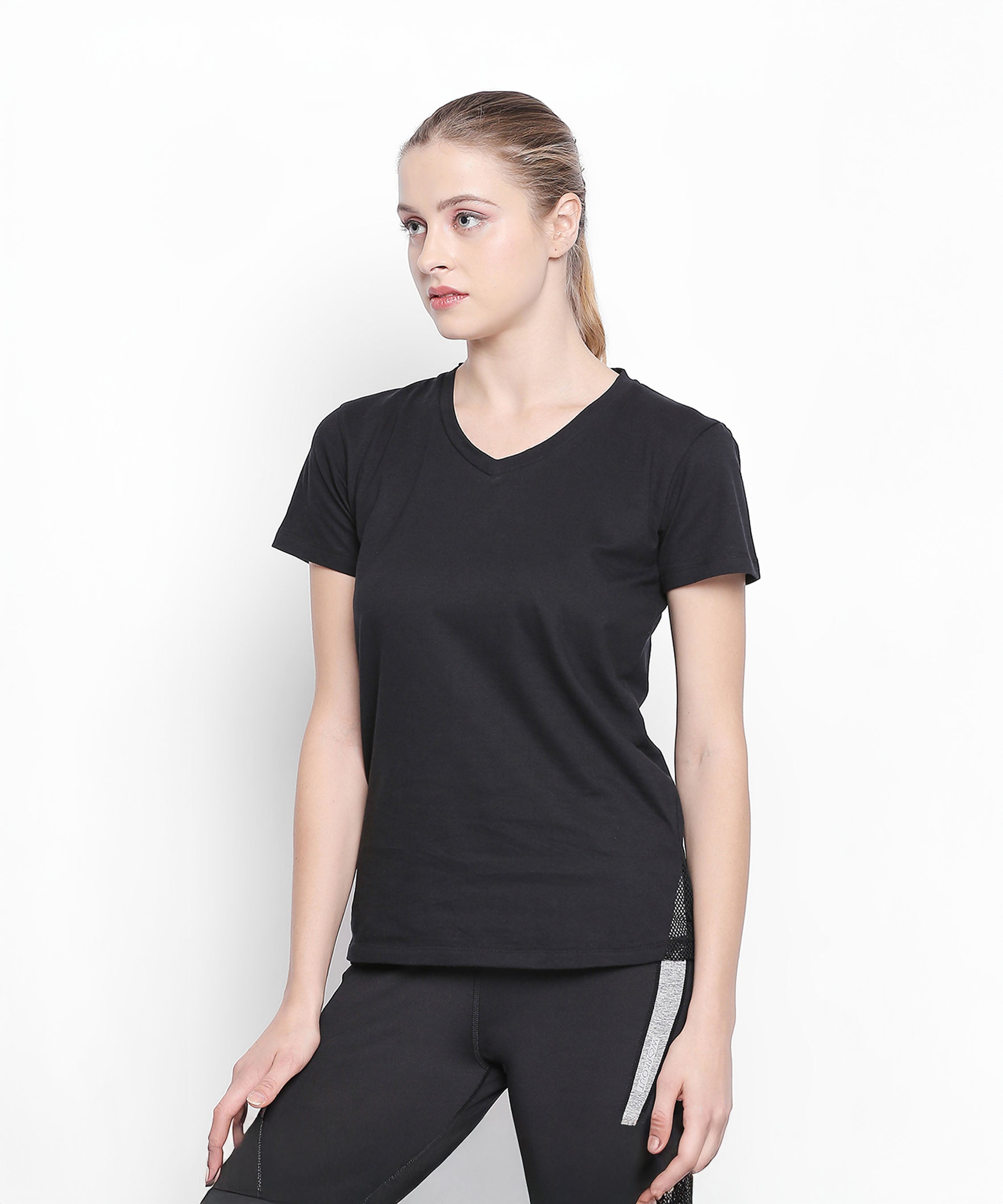 Woman in a Tuna London Sara Basic Sports Tee with net detailing, paired with black pants, standing against a plain white background.