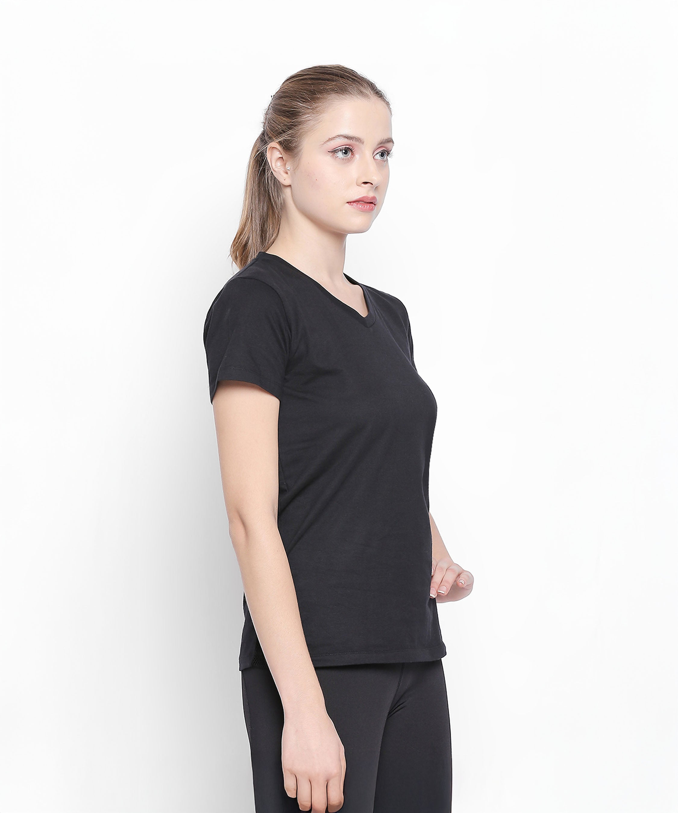 A woman wearing the Tuna London Sara Basic Sports Tee With Net Detailing for Women in black and matching pants stands sideways against a plain white background.