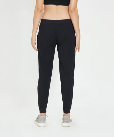 A person wearing Joggers - Ashtanga Series Black and sneakers, shown from the back, stands against a white background.