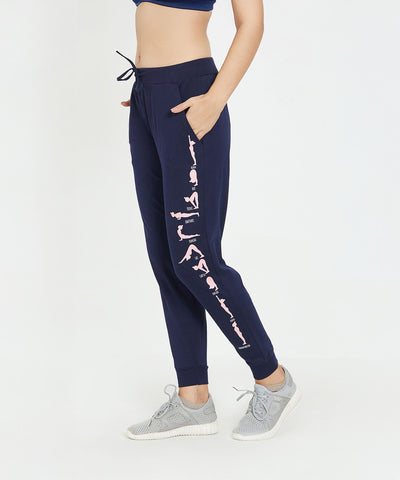 Woman wearing Joggers - Ashtanga Series Blue, gray sneakers, and a navy sports bra, against a white background.