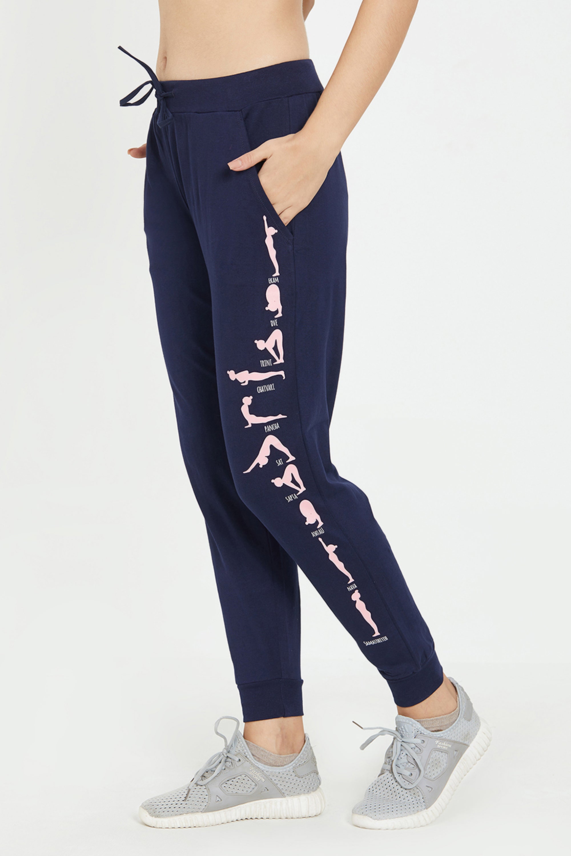 Fashion-forward women will love the Joggers - Ashtanga Series Blue, featuring playful pink yoga pose illustrations on the side, effortlessly paired with gray sneakers.