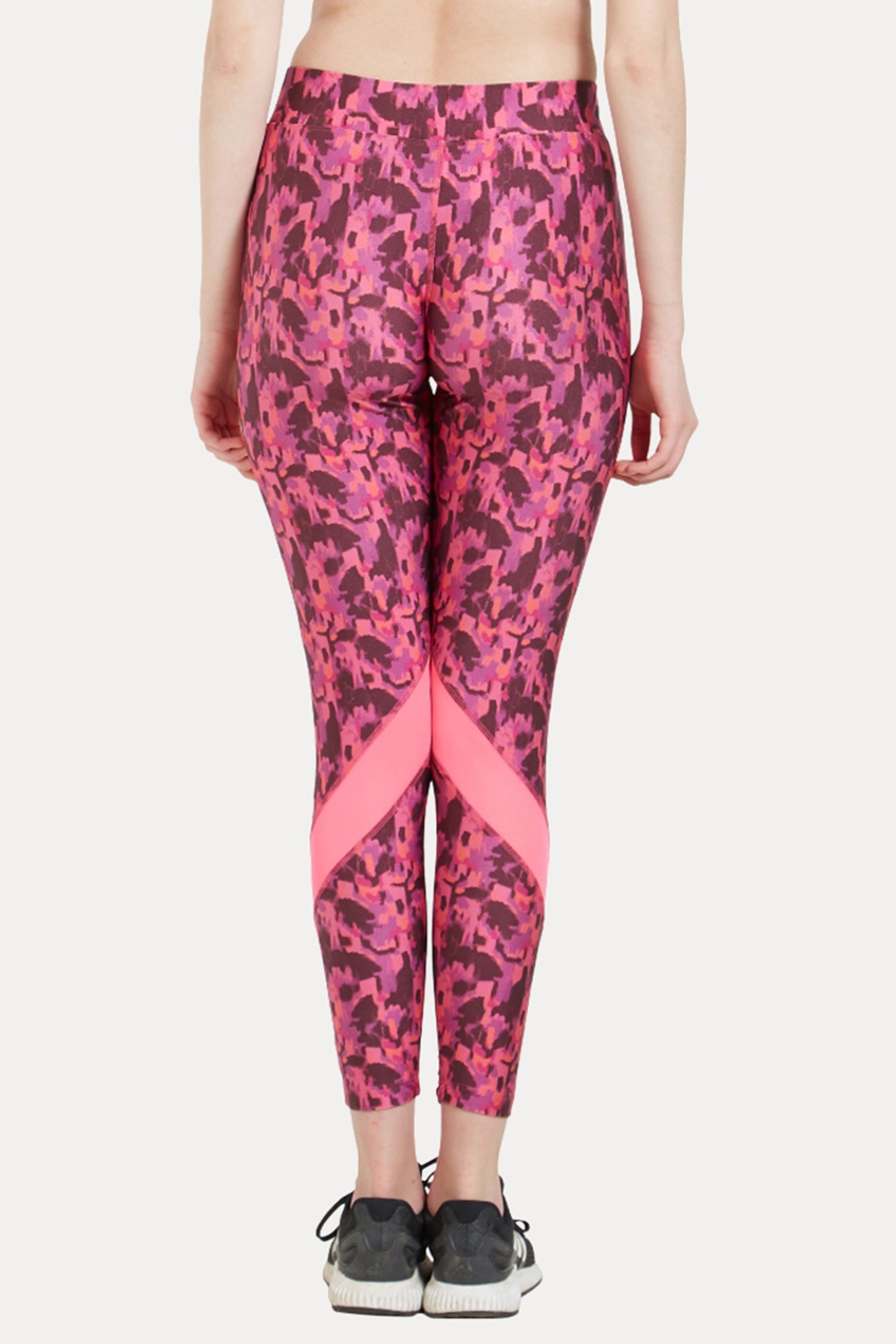 A person seen from behind wears the Printed Slim Fit Track Pant LUSH by TUNA LONDON—pink patterned poly spandex track pants with a light pink "X" design on the calves—paired with black sneakers.