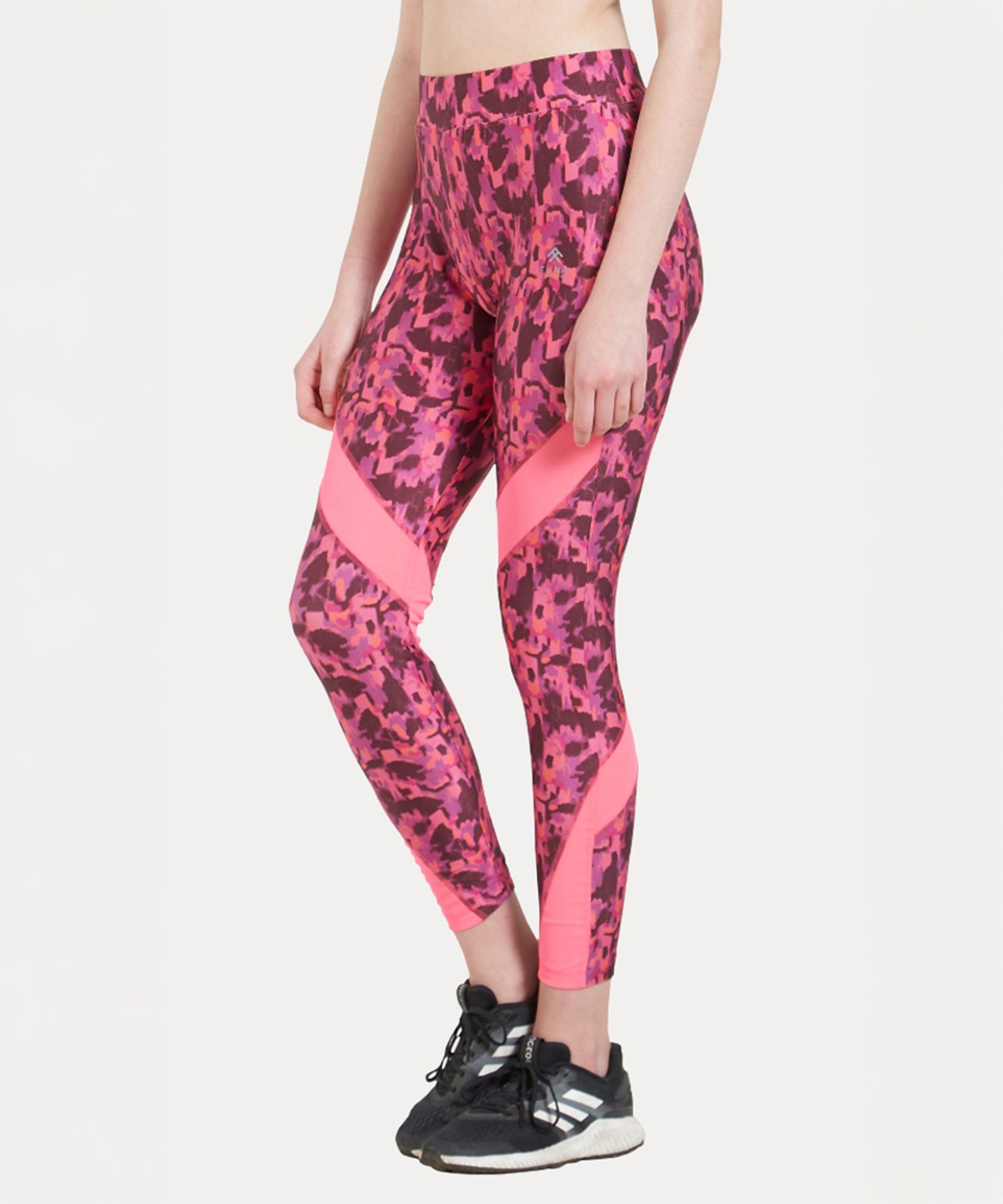 Person wearing the Printed Slim Fit Track Pant LUSH in pink, featuring a high-rise waistband and prints, paired with black sneakers against a plain white background.