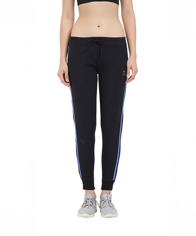 Woman wearing Classic Joggers TLC02SS featuring a sporty side stripe and tapered fit, paired with a black sports bra and gray sneakers, standing on a white background.