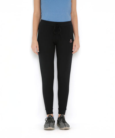 A woman in Black Classic Joggers TLC02 with a slim tapered fit, paired with a blue top and sneakers, stands against a plain white background.